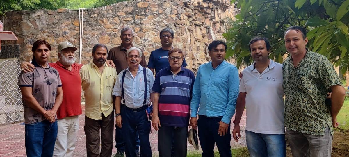 Group photograph of GATGA members in a garden beside a stone wall