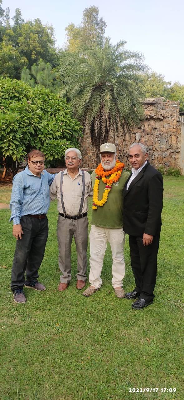 Vipin Bhardwaj garlanded and surrounded by three colleagues in a garden