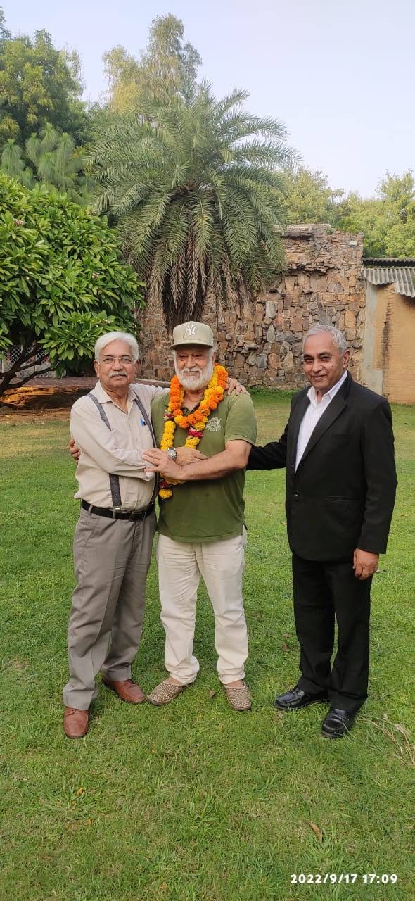 Vipin Bhardwaj garlanded with two colleagues in a garden