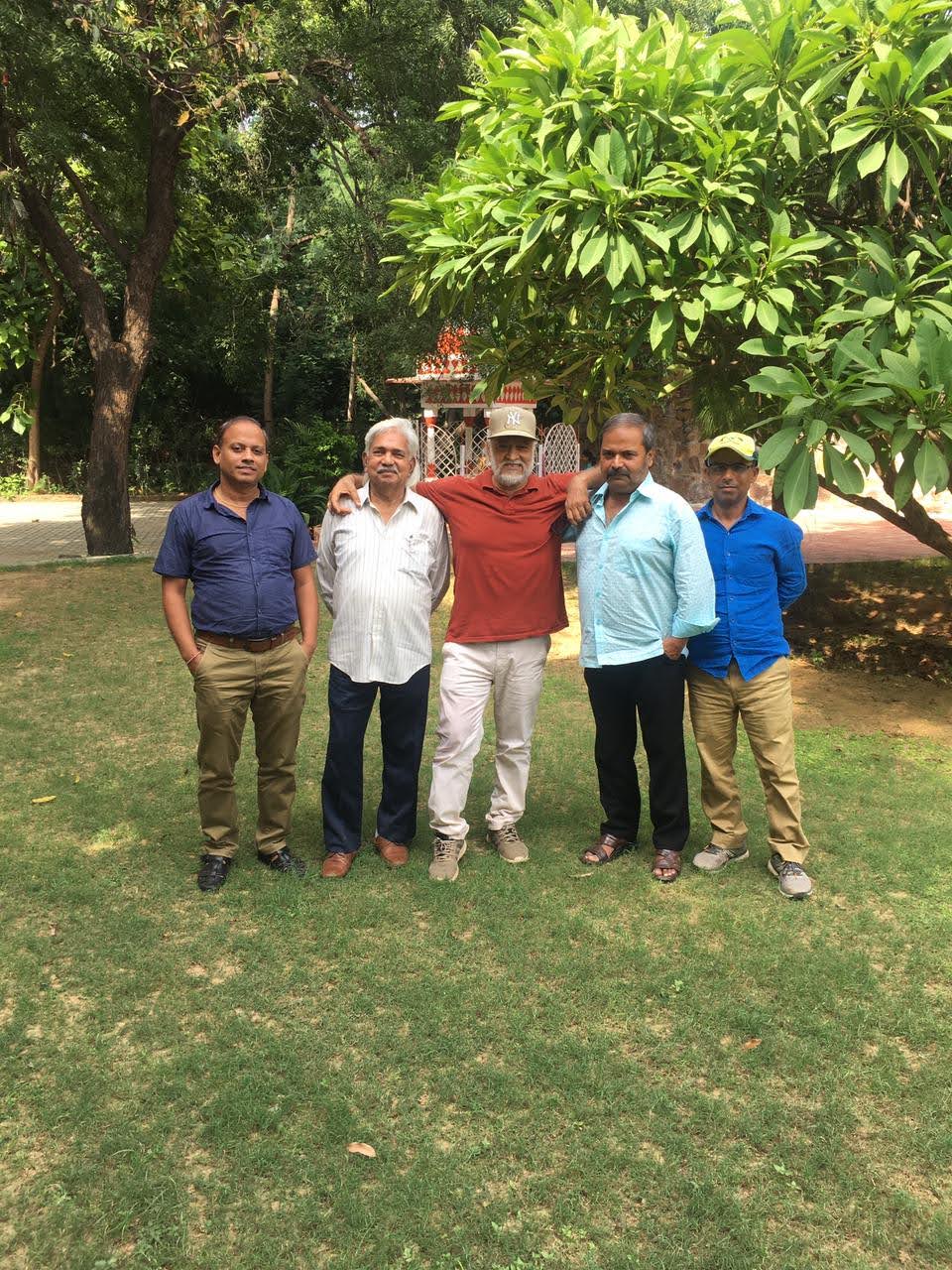Group of five members photographed together under a tree