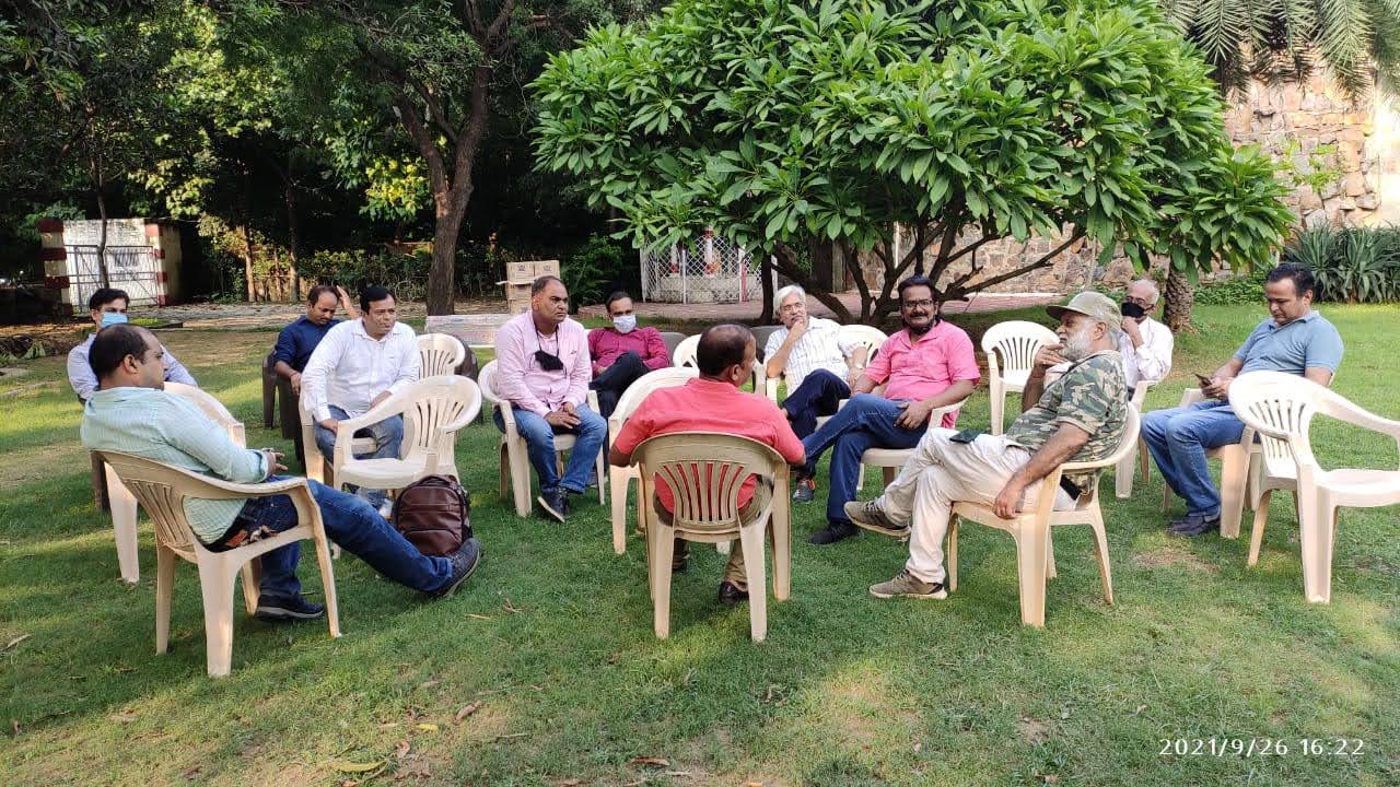 Members seated in a circle for an open-air meeting on a lawn