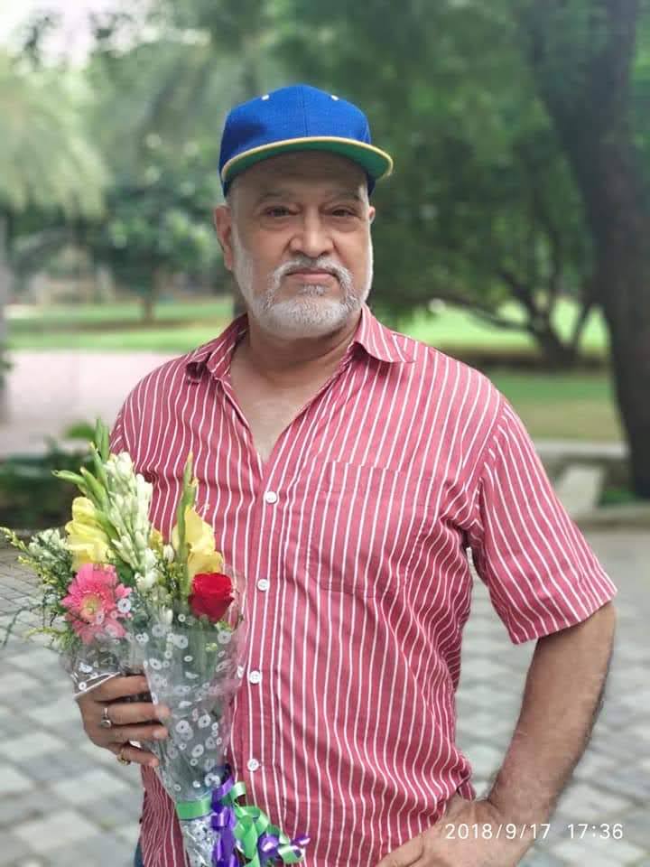 Portrait of Vipin Bhardwaj holding a bouquet of flowers in a park