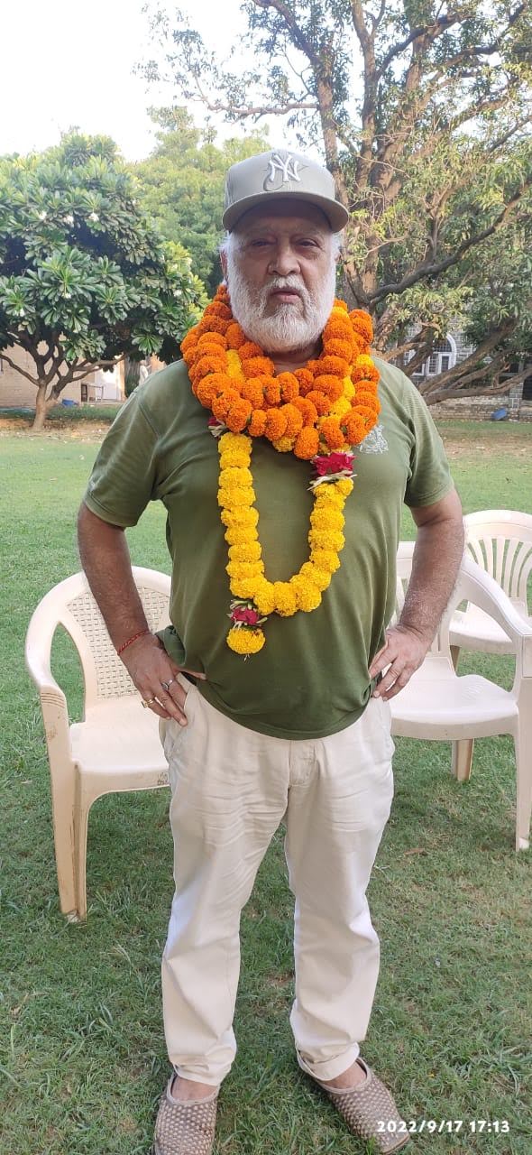Vipin Bhardwaj wearing two marigold garlands after being felicitated